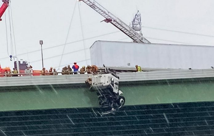 Uma forte tempestade deixou este motorista preso em uma ponte com seu caminhão balançando acima de um rio